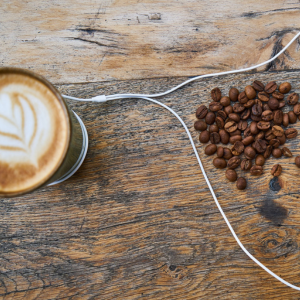 Cappuccino mit Kopfhörer auf dem Tisch und Kaffeebohnen